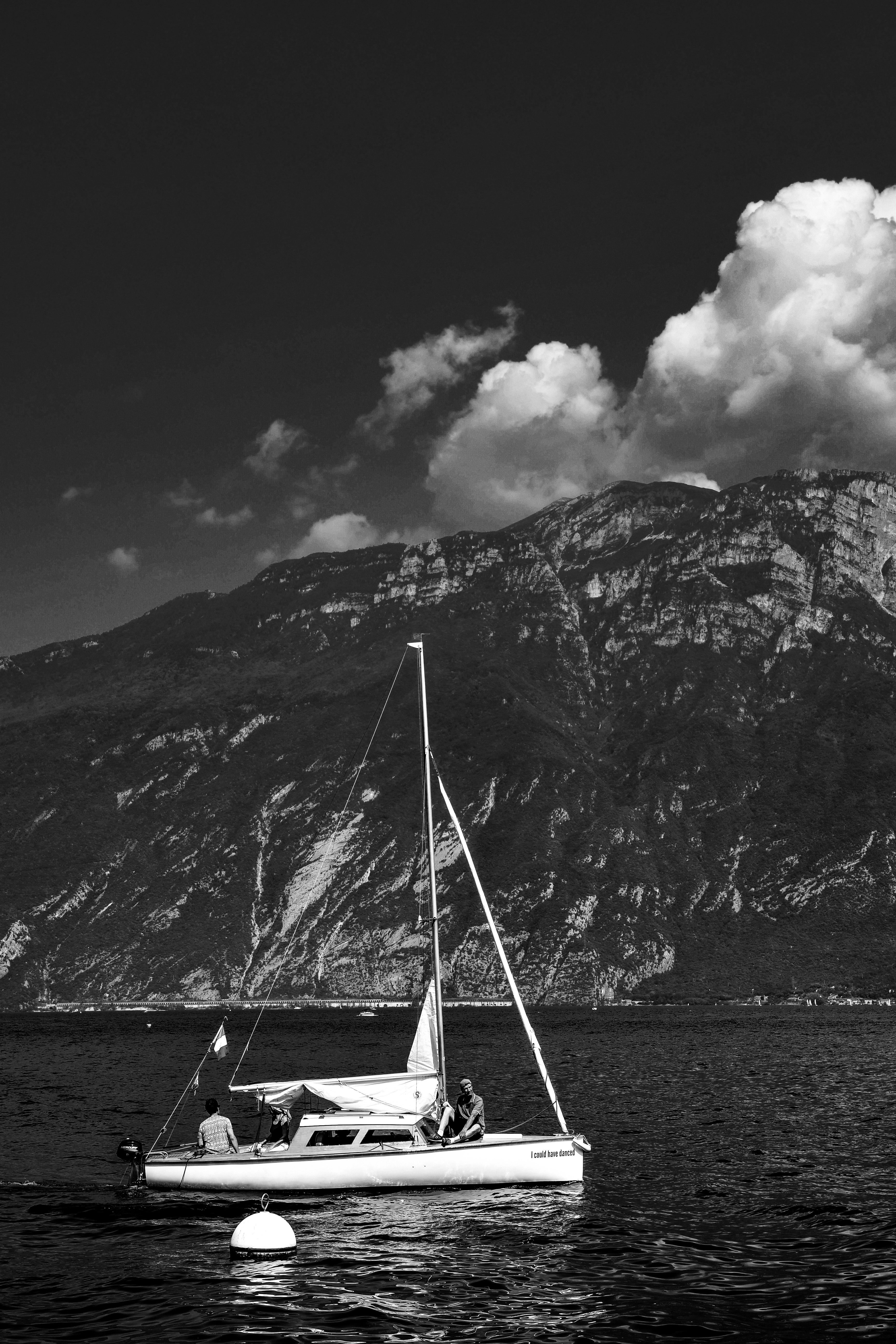 grayscale photography of sailing boat under cloudy sky